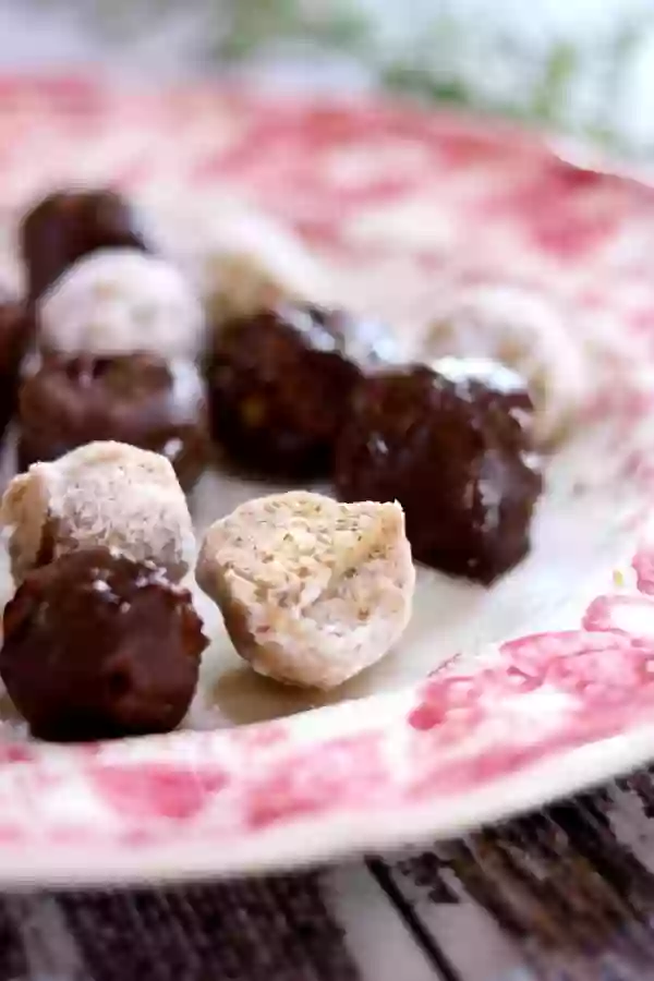 Chocolate covered and sugar covered bourbon balls arranged on a plate.