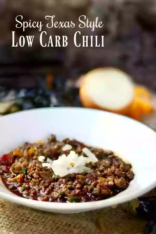 Low Carb chili garnished with chopped onions in a white dish with a cut onion in the background