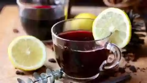 Horizontal image of low carb hot mulled wine in two punch cups garnished with lemon slices - featured image