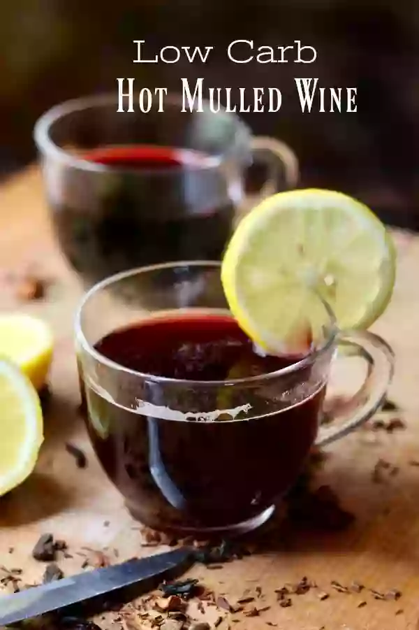Two glass punch cups hold dark ruby red low carb hot mulled wine. A lemon slice garnishes the cup