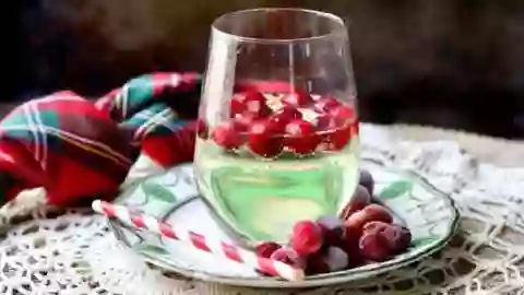 balloon glass filled with low carb white wine spritzer, with frozen cranberries floating in it. Feature image