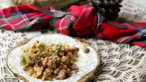 Feature image - a plate of low carb stuffing sits on a lace covered table with a red plaid napkin in the background. The plate has gold trim