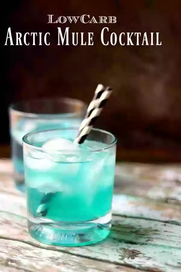 Low carb arctic mule cocktail is bright blue with black and white striped straws in the glass. Title image