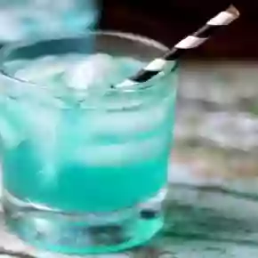 feature image for the low carb vodka cocktail - blue cocktail in an on the rocks glass with a black and white straw
