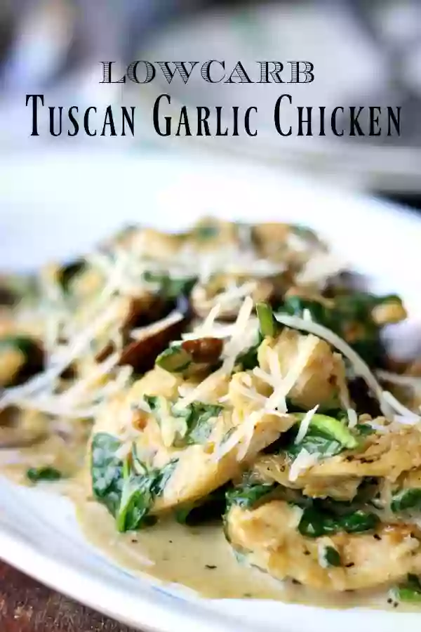 Closeup of low carb Tuscan garlic chicken, tender pieces of chicken, olives, and spinach in a creamy sauce - on a vintage white platter with a blue rim. title image