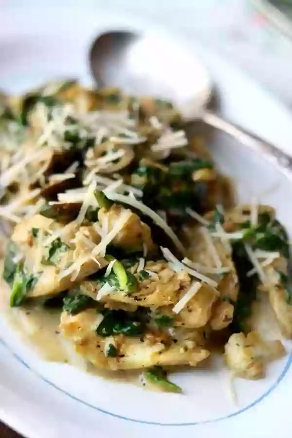 Tender Pieces of Tuscan Garlic Chicken in a Creamy Sauce With Spinach and Olives - Parmesan Cheese Is Sprinkled on Top