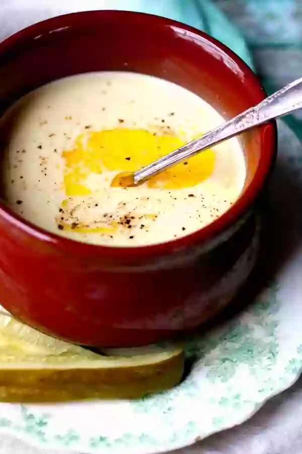 Low Carb Dill Pickle Soup in a Reddish Soup Bowl With Melted Butter Floating on the Top. 