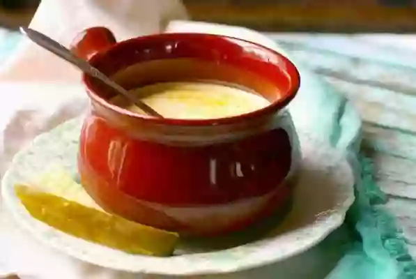 feature image for low carb dill pickle soup - dill pickle soup in a reddish soup bowl on a chipped painted table.