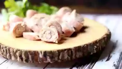 Low carb ham pinwheels on a rough wood platter with a dark background