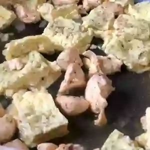 Pieces of chicken and squares of dumpling in a saute pan