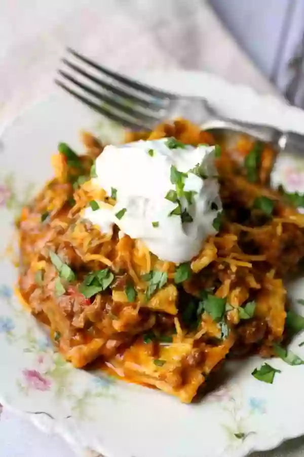 closeup of low carb taco casserole with a dollop of sour cream and a fork in the background