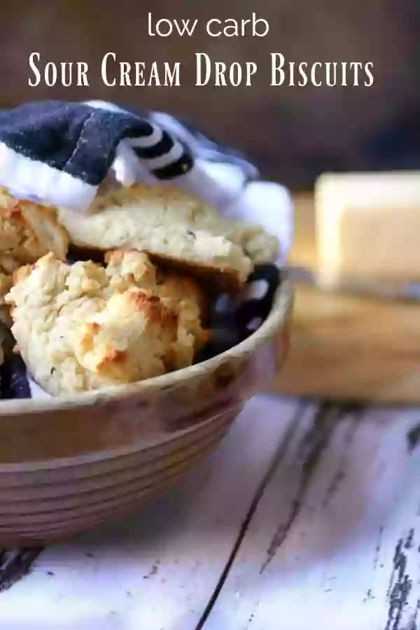 Low carb sour cream biscuits title image -biscuits in a vintage yellow-ware bowl on a chippy wood table