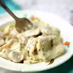 A tarnished silver fork is in a bowl of Southern chicken and dumplings - recipe image