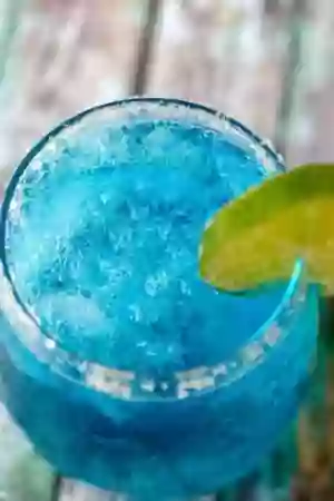 Closeup of the bright blue low carb cocktail Ocean Breeze. A lime wheel garnishes the glass.