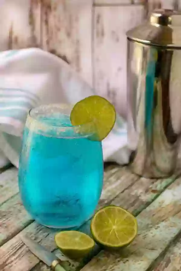 Ocean Breeze blue low carb cocktail in a glass on a chipped painted table.
