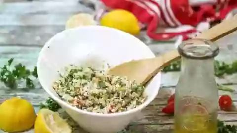 Cauliflower tabbouleh in a white bowl with lemons at the base.