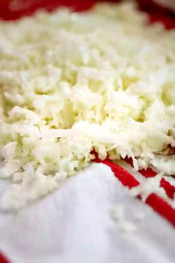 Grated cauliflower on a white and red towel.