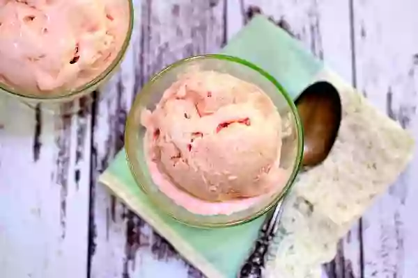A closeup of a scoop of low carb strawberry ice cream in a vintage ice cream dish.