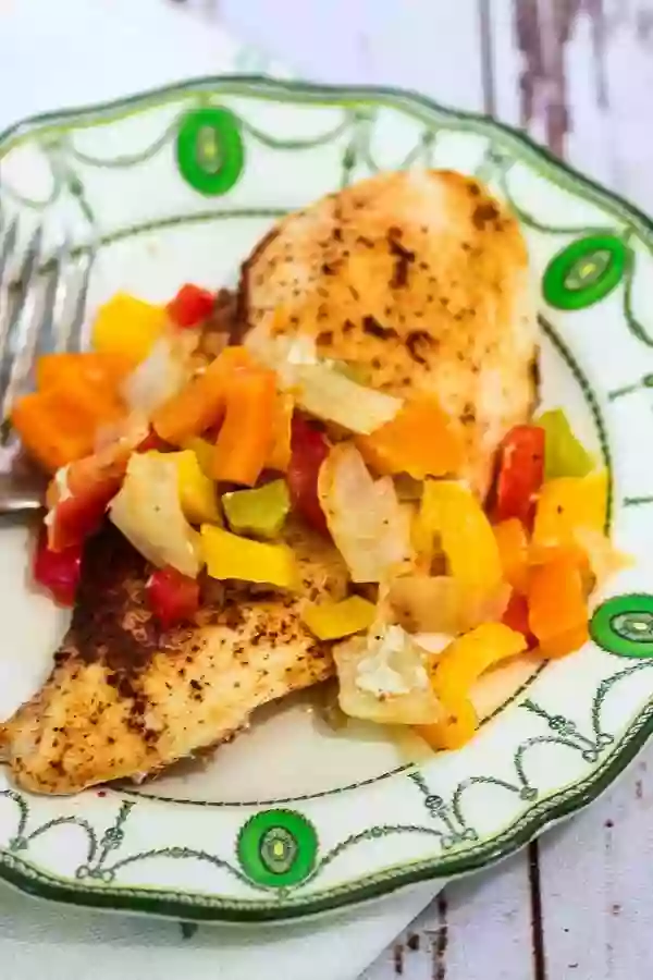 Easy sheet pan chicken fajitas on a plate with diced Bell peppers of all colors.