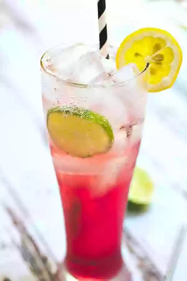 A closeup of a red mai tai cocktail garnished with lime