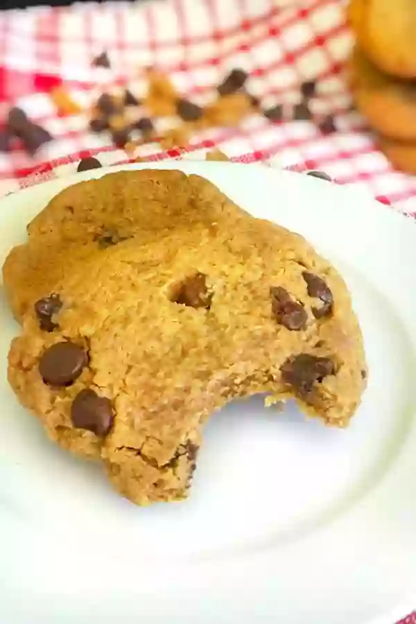 Peanut butter chocolate cookies on a white plate with chocolate chips in the background