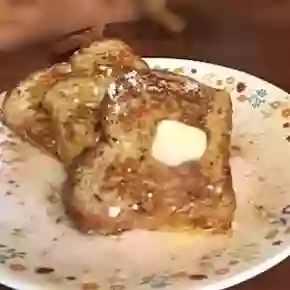 Cinnamon French toast on a white flowered plate with a pat of butter on top.