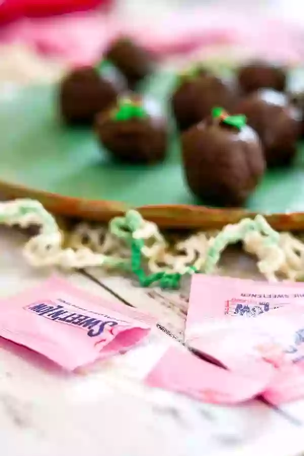 Packets of sweet 'n low with chocolate truffles in the background