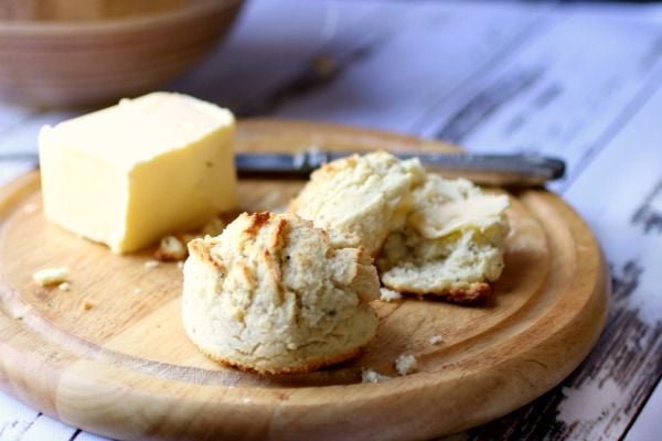 Easy low carb sour cream biscuits are golden brown. On a wooden dish with butter in the background