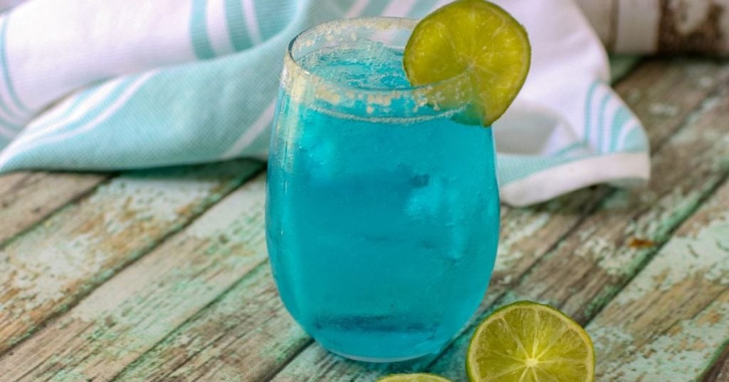 Ocean Breeze low carb cocktail is on a table surrounded but cut limes. SOcial media image